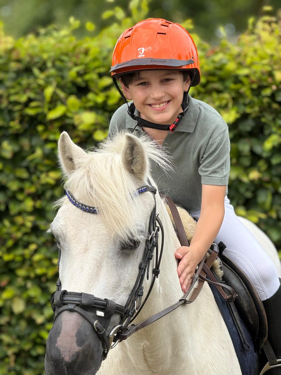 Een jonge ruiter op een witte pony bij Manege Meijer